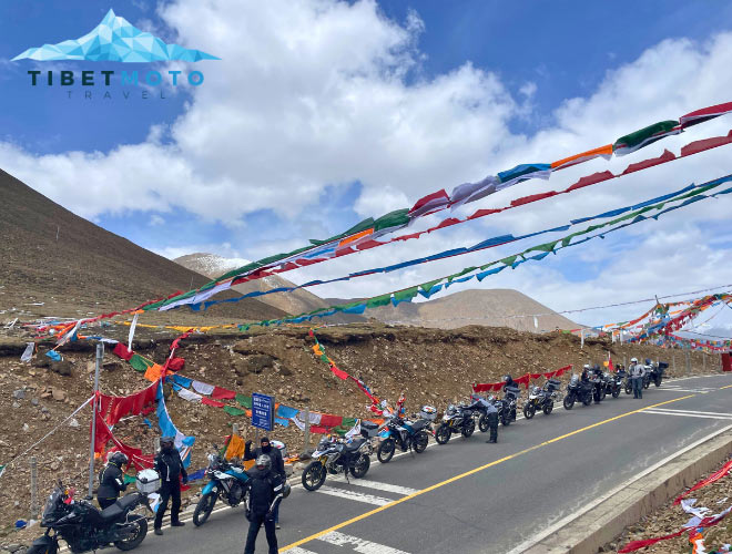 A brief stop during a motorcycle tour beneath prayer flags in Tibet.