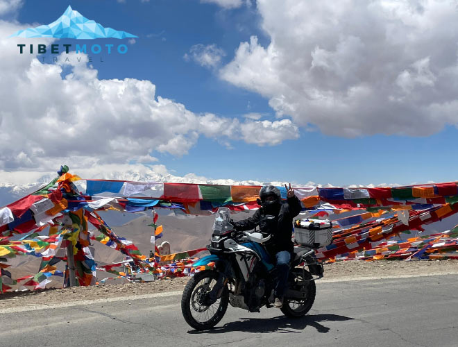 Motorcyclist rides past prayer flags in Tibet.