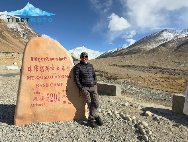 Traveler at the monument in the base camp in Tibet, with a view of Mount Everest.