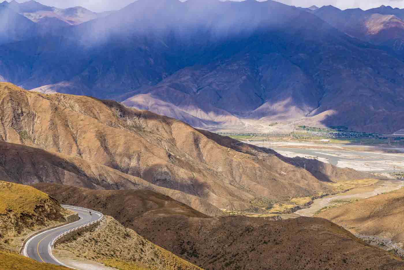 mountain road descending toward the qomolangma region tibet A winding mountain road descends into the Qomolangma region, revealing the dramatic landscapes of Tibet.